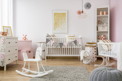 Cette image montre une chambre de bébé fille nordique de taille moyenne avec un mur blanc, parquet clair et un sol marron.