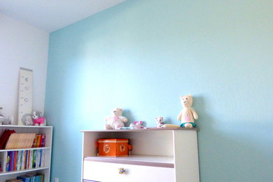 Diseño de habitación de bebé neutra contemporánea de tamaño medio con paredes azules, suelo vinílico y suelo beige