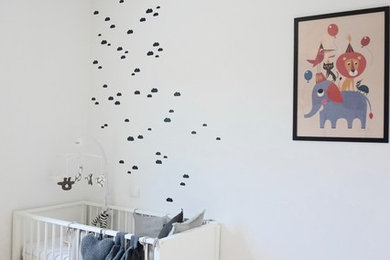 Cette image montre une chambre de bébé neutre design de taille moyenne avec un mur blanc et sol en béton ciré.