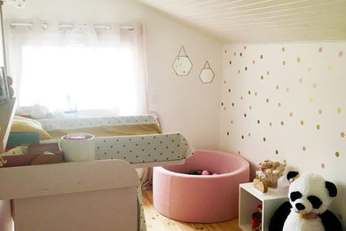 Réalisation d'une chambre de bébé fille design avec parquet clair, un mur blanc et un sol marron.