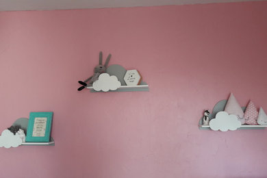 Aménagement d'une grande chambre de bébé fille avec un mur gris et un sol en bois brun.