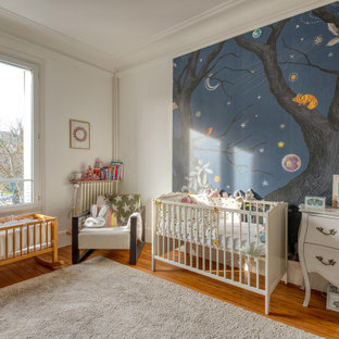 Inspiration pour une chambre de bébé design avec un mur blanc, un sol en bois brun et un sol marron.