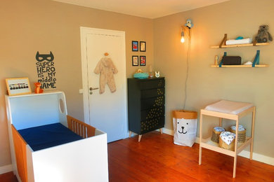 Cette image montre une chambre de bébé garçon nordique de taille moyenne avec un mur beige, un sol en bois brun et un sol marron.
