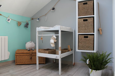 Diseño de habitación de bebé neutra de estilo de casa de campo pequeña con paredes multicolor y suelo de madera clara