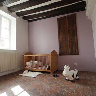 Esempio di una grande cameretta per neonata country con pareti rosa e pavimento in terracotta
