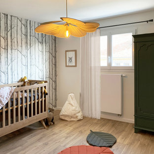 Réalisation d'une grand chambre de bébé garçon nordique avec un mur blanc, un sol en bois clair et un sol marron.