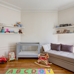 Inspiration pour une grand chambre de bébé neutre traditionnelle avec un mur blanc et un sol en bois brun.