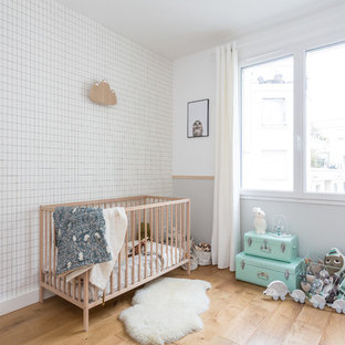Exemple d'une chambre de bébé neutre tendance de taille moyenne avec un mur gris, un sol beige et un sol en bois brun.