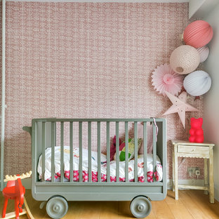 Foto de habitación de bebé niña bohemia, de tamaño medio, con paredes rosas, suelo de madera clara y suelo beige