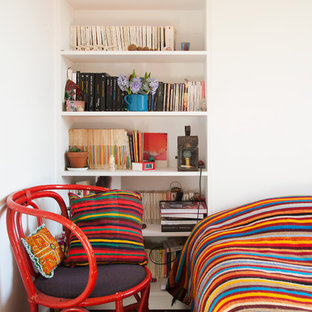 Cette photo montre une chambre parentale tendance de taille moyenne avec un mur blanc et un sol en bois brun.