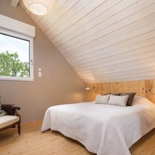 Inspiration pour une chambre mansardée ou avec mezzanine design avec un mur beige et un sol en bois brun.