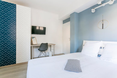 Idée de décoration pour une chambre parentale minimaliste de taille moyenne avec un mur bleu, parquet clair et un sol beige.
