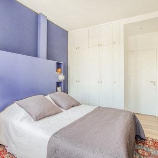 Réalisation d'une chambre design avec un mur violet, un sol en bois clair, aucune cheminée et du papier peint.
