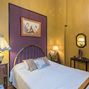Modelo de habitación de invitados bohemia con paredes multicolor, suelo de madera en tonos medios y suelo marrón