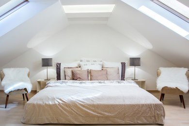 Diseño de dormitorio principal clásico renovado grande sin chimenea con paredes blancas y suelo de madera clara