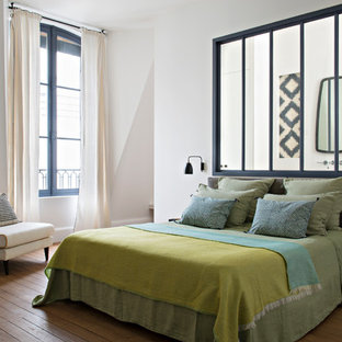 Inspiration pour une chambre parentale design avec un mur blanc, un sol en bois brun et un sol marron.