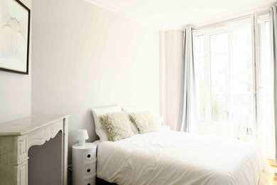 Imagen de dormitorio principal contemporáneo pequeño con paredes grises, suelo de madera clara y chimenea de esquina