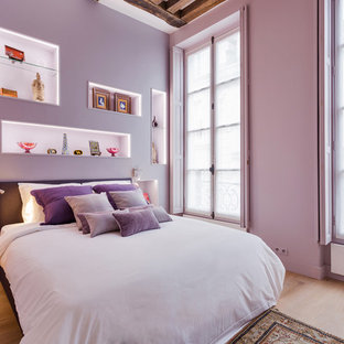Réalisation d'une grand chambre parentale bohème avec un mur violet, un sol en bois clair et un sol beige.