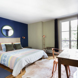 Idée de décoration pour une grand chambre parentale design avec un mur bleu et un sol en bois brun.