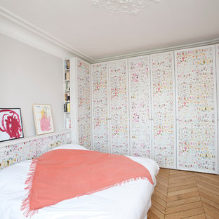 Aménagement d'une chambre parentale contemporaine de taille moyenne avec un mur multicolore et un sol en bois brun.