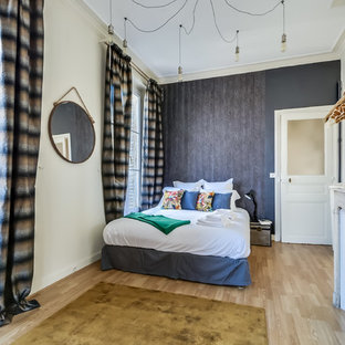 Aménagement d'une grand chambre parentale classique avec un sol en bois clair, une cheminée standard et un mur gris.