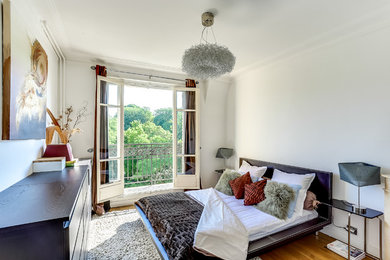 Modernes Schlafzimmer ohne Kamin mit weißer Wandfarbe und braunem Holzboden in Paris