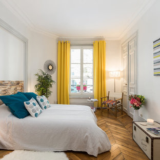 Réalisation d'une chambre parentale design avec un mur blanc, un sol en bois brun et un sol marron.