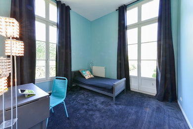 Cette photo montre une chambre avec moquette éclectique avec un mur bleu.