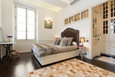 Cette photo montre une grande chambre parentale tendance avec un mur blanc et parquet foncé.