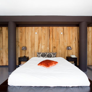Aménagement d'une grand chambre parentale contemporaine avec un mur marron et béton au sol.