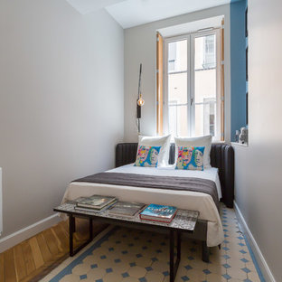 Idée de décoration pour une chambre d'amis bohème avec un mur beige, un sol en bois brun et un sol multicolore.