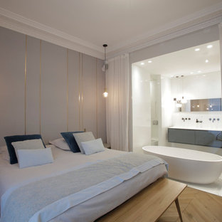 Inspiration pour une grand chambre parentale design avec un mur gris, un sol en bois clair et aucune cheminée.