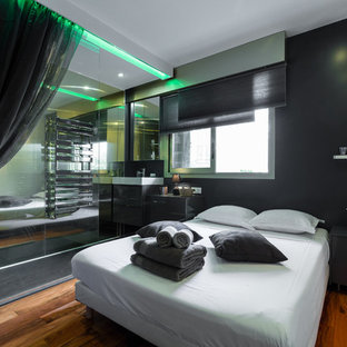 Cette photo montre une chambre parentale tendance de taille moyenne avec un mur noir et un sol en bois brun.