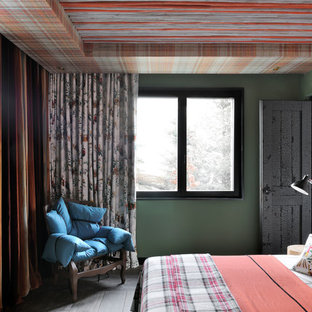 Idée de décoration pour une chambre d'amis bohème avec un mur vert, un sol en bois brun et un sol gris.