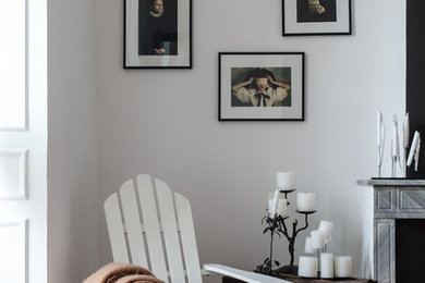 Cette photo montre une petite chambre d'amis tendance avec un mur blanc, tomettes au sol, une cheminée standard et un manteau de cheminée en pierre.