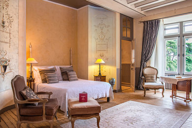 Foto de dormitorio principal clásico renovado grande con paredes beige, suelo de madera en tonos medios, todas las chimeneas, marco de chimenea de piedra y suelo marrón