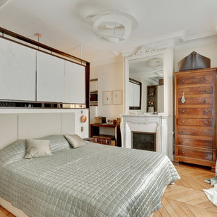 Exemple d'une chambre parentale chic de taille moyenne avec un mur blanc, un sol en bois clair, une cheminée standard et un sol marron.