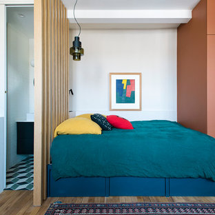 Exemple d'une petit chambre mansardée ou avec mezzanine éclectique avec un mur blanc et un sol en bois clair.