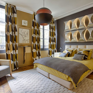 Exemple d'une grand chambre parentale rétro avec un mur jaune, un sol en bois clair, aucune cheminée et un sol marron.