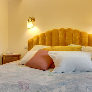 Modelo de dormitorio principal, retro, pequeño, con parades naranjas, suelo laminado y suelo marrón