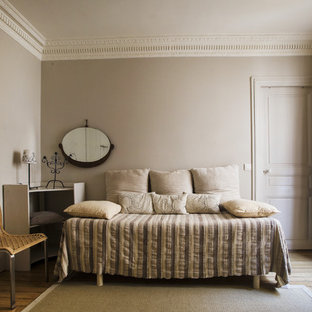 Inspiration pour une chambre d'amis design de taille moyenne avec un mur beige et un sol en bois brun.
