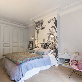 Cette photo montre une chambre éclectique avec un mur gris, un sol en bois clair et un sol beige.