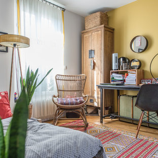 Cette photo montre une chambre éclectique avec un mur jaune, un sol en bois brun et un sol marron.