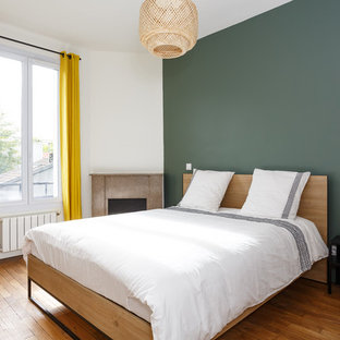 Aménagement d'une chambre contemporaine avec un mur vert, un sol en bois brun et un sol marron.