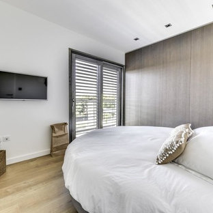 Cette image montre une chambre design avec un mur blanc, un sol en bois clair et un sol beige.