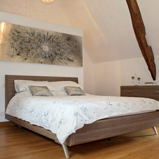 Réalisation d'une chambre parentale champêtre avec un mur blanc, un sol en bois brun et un sol marron.