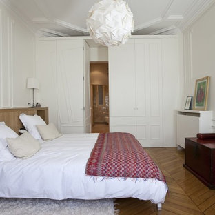 Idée de décoration pour une chambre tradition avec un mur blanc, un sol en bois brun et un sol marron.