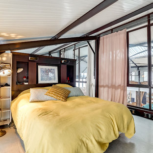 Aménagement d'une grand chambre mansardée ou avec mezzanine industrielle avec un sol gris.