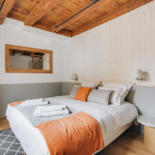 Réalisation d'une chambre chalet avec un mur blanc, un sol en bois brun et un sol marron.