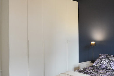 Cette photo montre une chambre parentale moderne de taille moyenne avec un mur bleu, parquet clair et aucune cheminée.